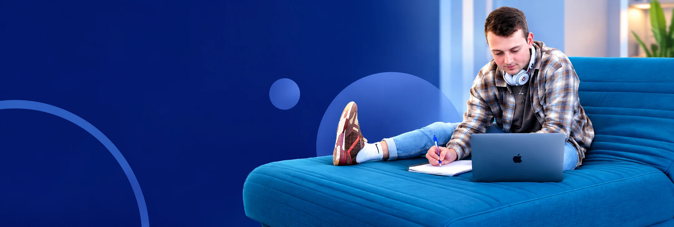 Man relaxing on a blue sofa with a laptop